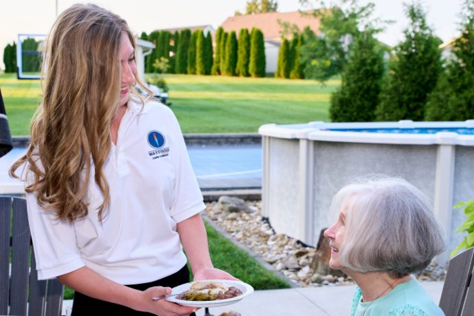 A Caregiver bringing a client a meal outdoors
