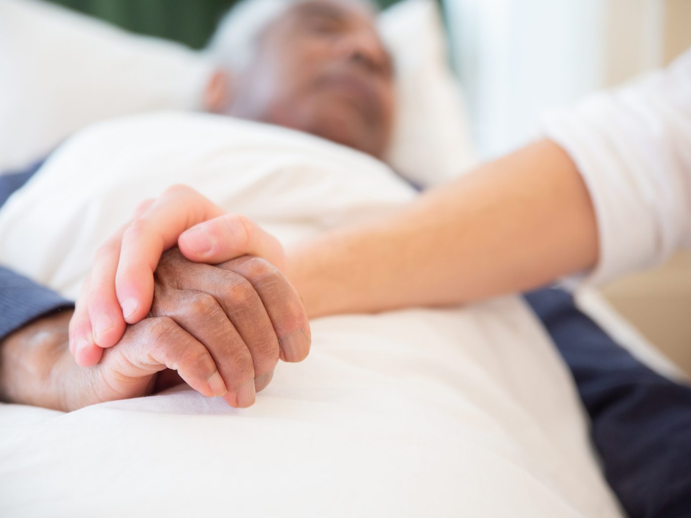 Two hands held together at a bedside