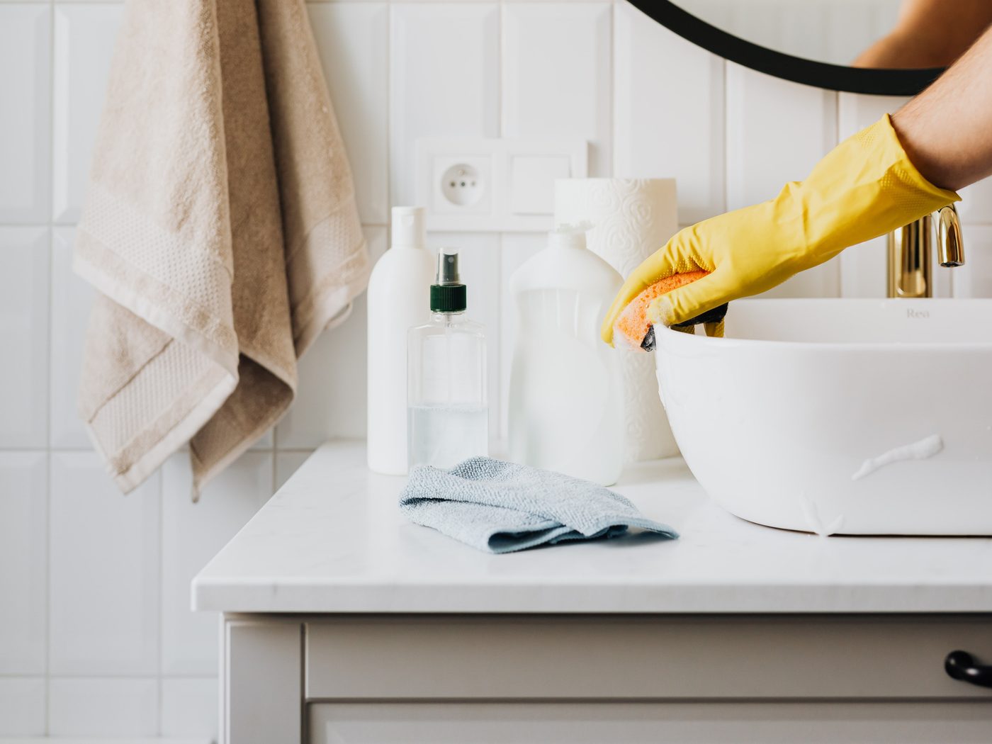 A gloved hand cleaning a bathroom basin